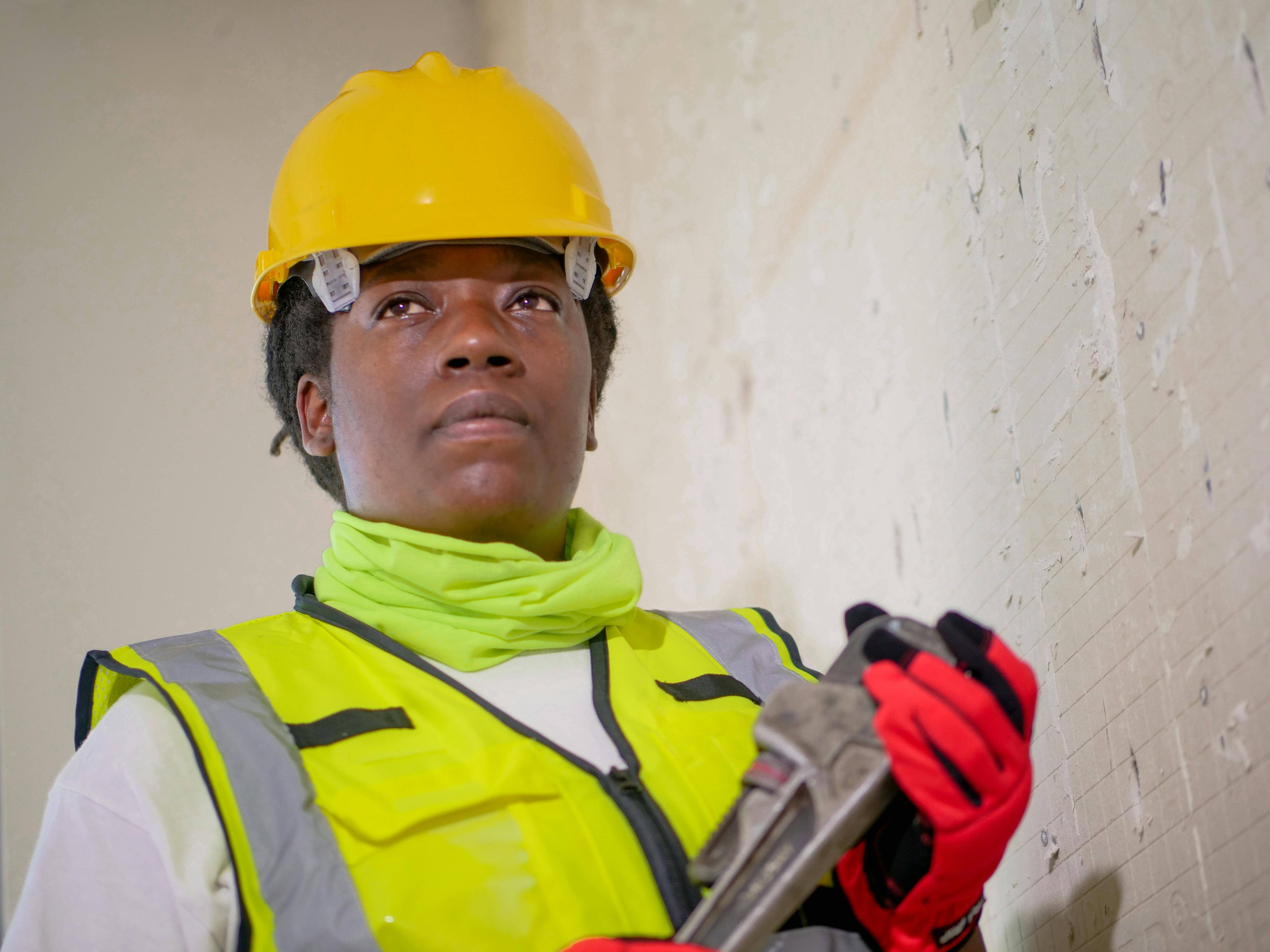 Handywoman wearing a hard hat and holding a wrench.