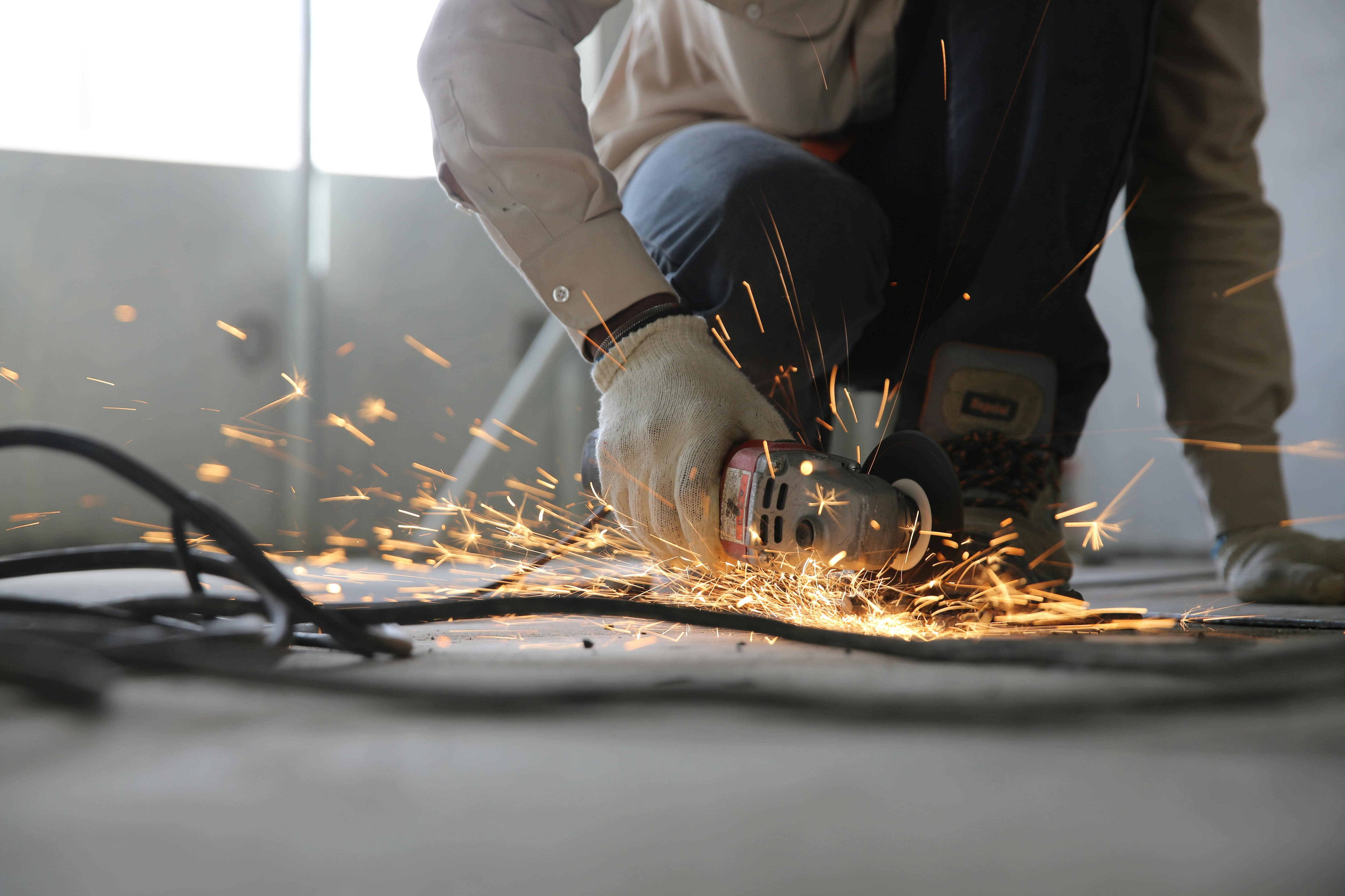 A person in the trades using a saw on metal, which causes sparks. 