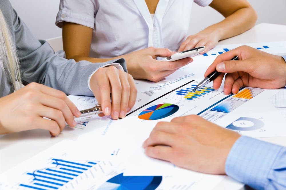 Close up of human hands and documents with graphs and diagrams